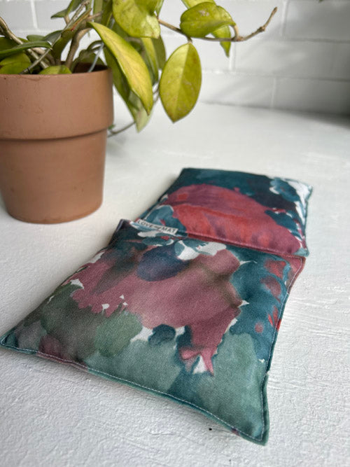 Floral-patterned yoga knee pillows on a white surface with a potted plant in the background