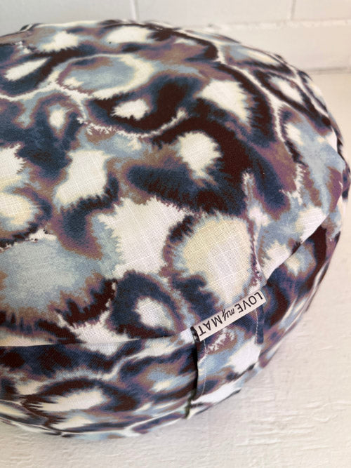 Round meditation floor cushion with an abstract and 'LOVE my MAT' tag and handle on a light background