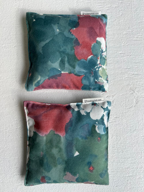 Two floral-patterned knee pillows on a textured white surface