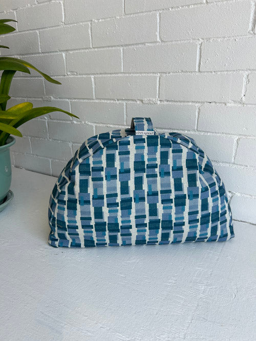 Blue and white checkered sit cushion on a white surface with a light gray tiled wall background