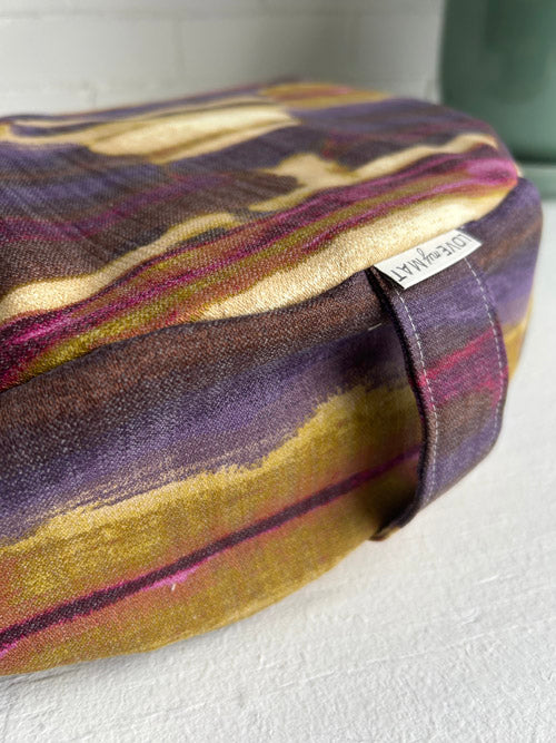 Multicolored fabric cushion with a visible brand label on a white surface