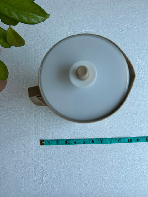 White lid on a beige Tupperware pitcher 