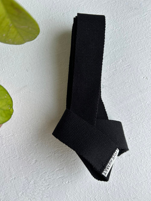 Black strap with a brand label on a light gray background