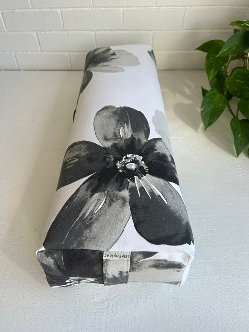 Floral-patterned Long Yoga Bolster on a white surface with a plant in the background