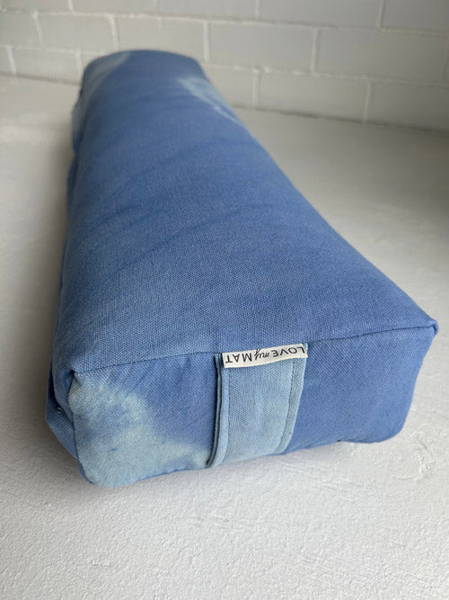 Blue tie dye bolster with a visible brand label on a white surface.