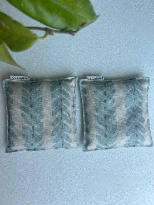 Two fabric knee pillows with leaf pattern on a light background