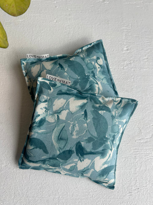 Two blue floral-patterned knee pads on a light gray surface with 'Love Me Mat' branding.