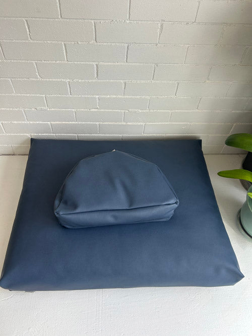 Blue vinyl meditation cushions on a white surface with a light gray tiled wall in the background