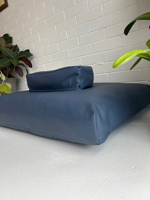 Blue meditation set against a white brick wall with plants around