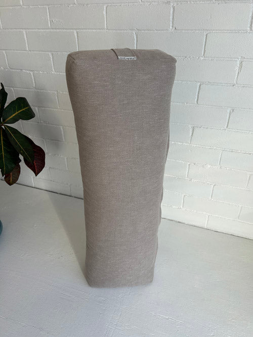 taupe long yoga bolster standing on end with white background