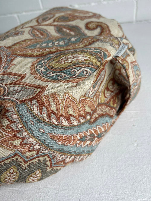Fabric meditation cushion with intricate paisley pattern on a white surface
