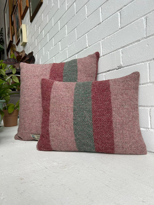Two striped cushions on a white surface with a white brick wall background