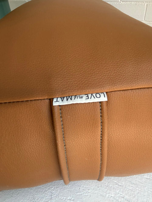 Brown vinyl bolster with a visible label on a textured surface