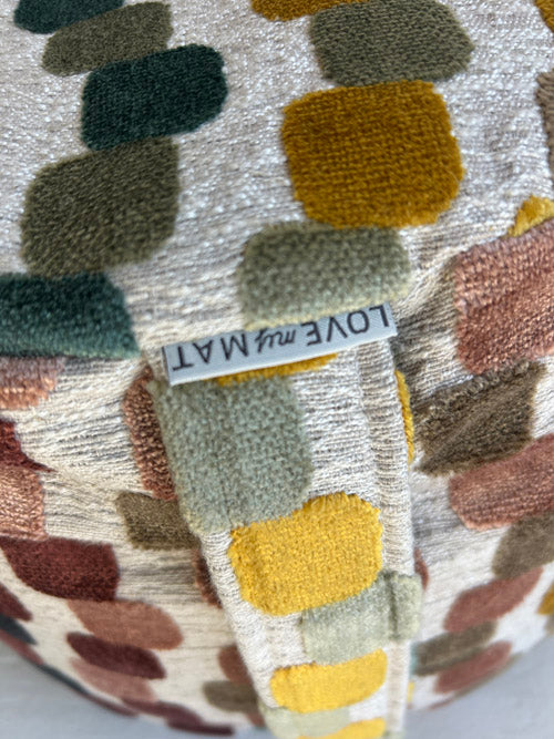 Close up of fabric Meditation Cushion with multicoloured squares and a label reading 'LOVE my MAT'.