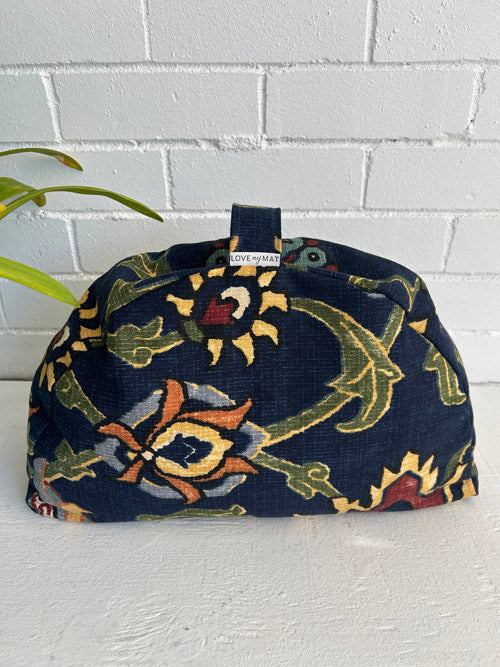 Meditation Sit Pillow in fun high contrast fabric with a handle and label against a white brick wall and on a white surface. 