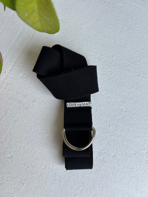 Black yoga strap with a silver ring on a light gray background