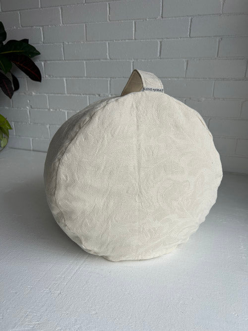 Cream Tall Meditation Cushion on a white surface with a light gray brick wall background