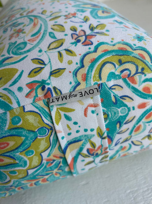 Colourful fabric yoga bolster with a pattern and a visible brand label on a white background