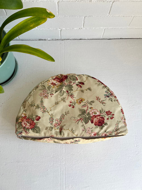 Floral-patterned fabric meditation floor pillow on a white surface with a plant in the background