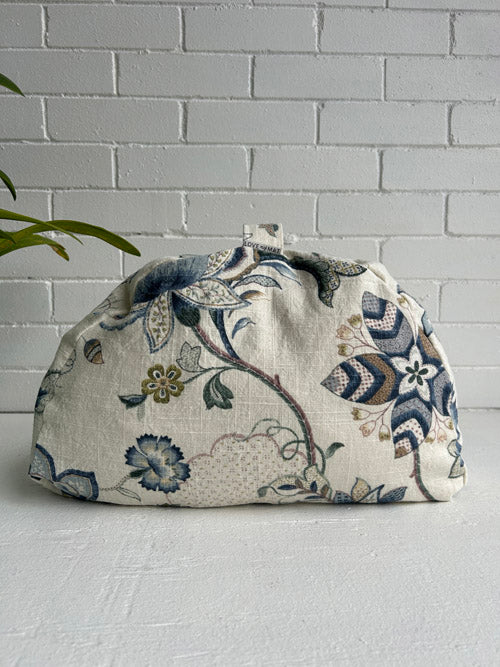 Floral-patterned fabric meditation cushion on a white surface with a white brick wall background