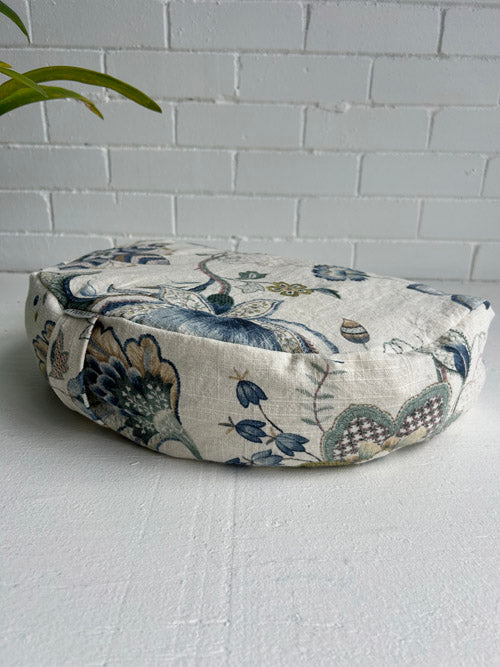 Decorative flor cushion with floral pattern on a white surface and light gray tiled wall background