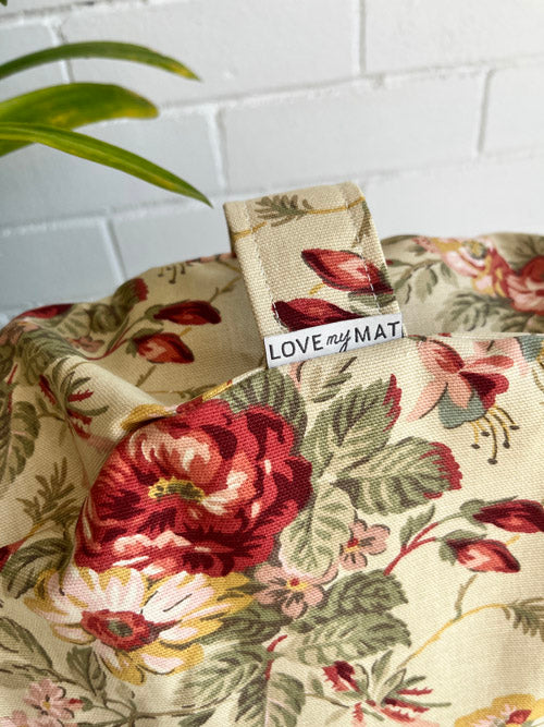 Floral-patterned mediation cushion and handle on its side  with a 'LOVE my MAT' tag on a white tiled background
