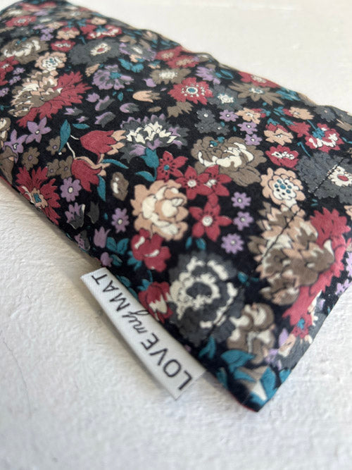 Floral-patterned  eye pillow with a visible brand label on a white background