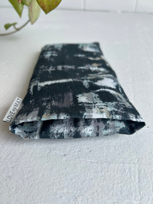 Close up of abstract patterned eye pillow insert area with a visible brand label on a light surface.