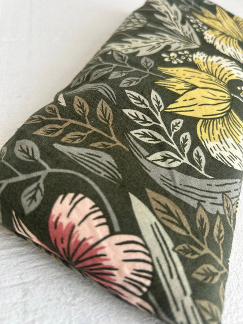 Floral patterned fabric eye pillow with leaves and flowers on a black background