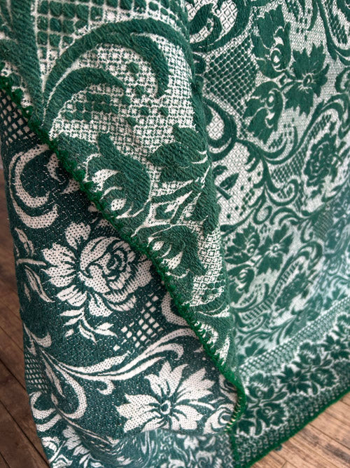 Green and white patterned wool blanket on a wooden surface