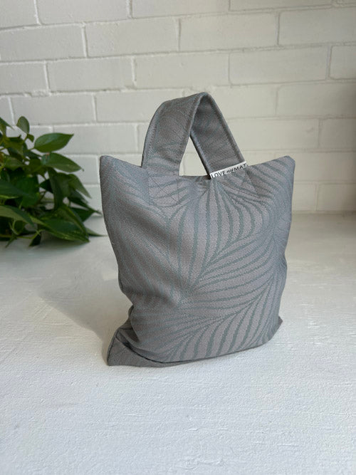 Gray textured weighted sandbag bag on a white surface with a plant in the background
