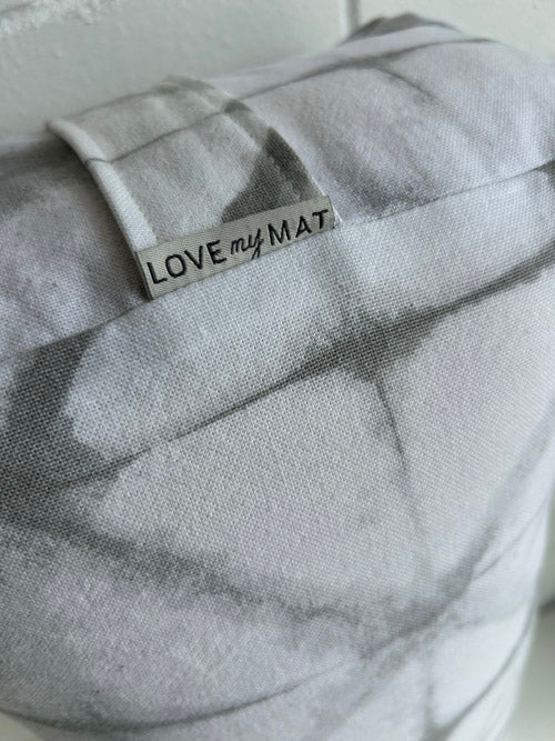 Close up of grey and white fabric yoga bolster with 'LOVE my MAT' label on a light background