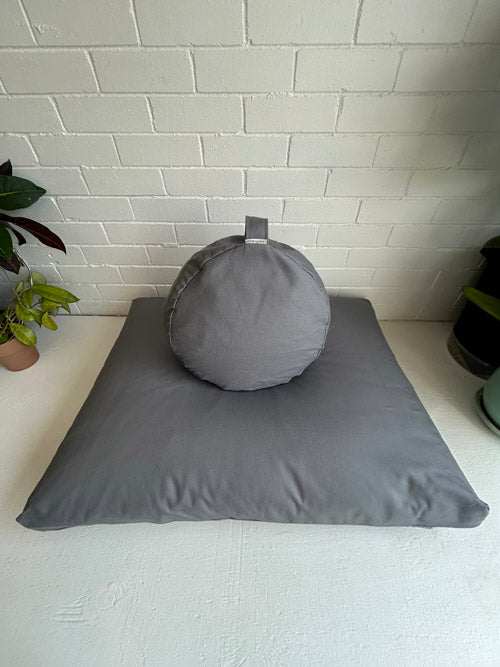 Gray meditation set on a white surface with a white brick wall background