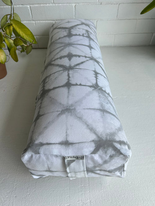 Long and lean yoga bolster with grey pattern on a white surface