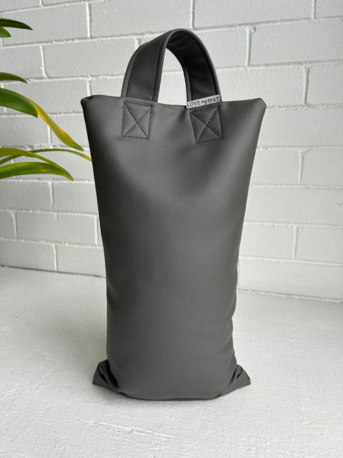 Grey Vinyl Sandbag on a white surface and white brick background