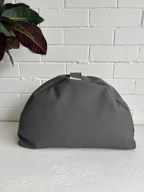 Gray floor cushion on a white surface with a white brick wall background