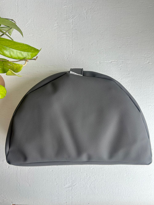 Gray floor cushion for meditation on a light gray background with a plant leaf in the corner