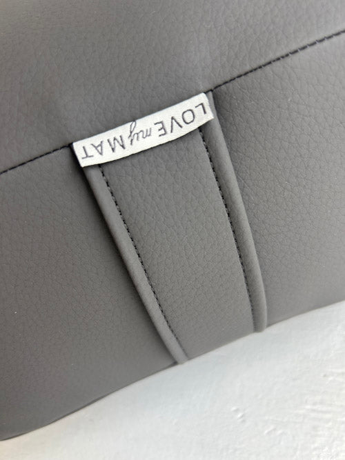 Close-up of a gray vinyl bolster product with a silver tag on a white background
