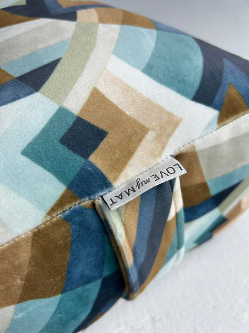 Multicolored geometric patterned yoga bolster with a visible brand label on a white background