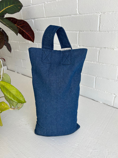 Blue denim sandbag on a white surface with a white brick wall background