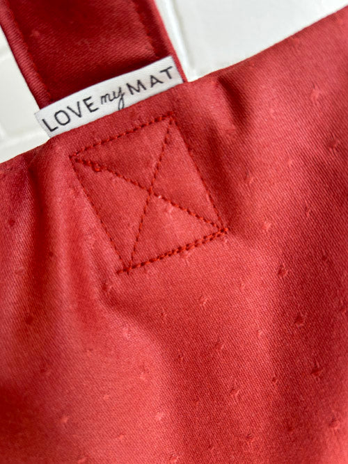 Close-up of a red fabric sandbag with a triangle pattern and 'LOVE my MAT' label.