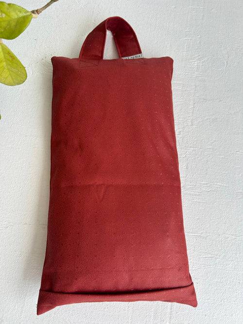 Red fabric sandbag with handles on a light gray background