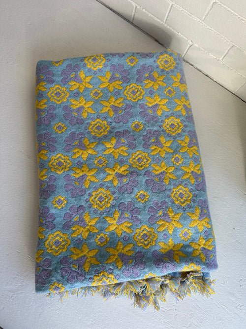 Floral patterned banket with blue and yellow colors on a white surface.