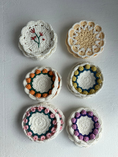 Set of six crocheted coasters with colorful patterns on a gray surface
