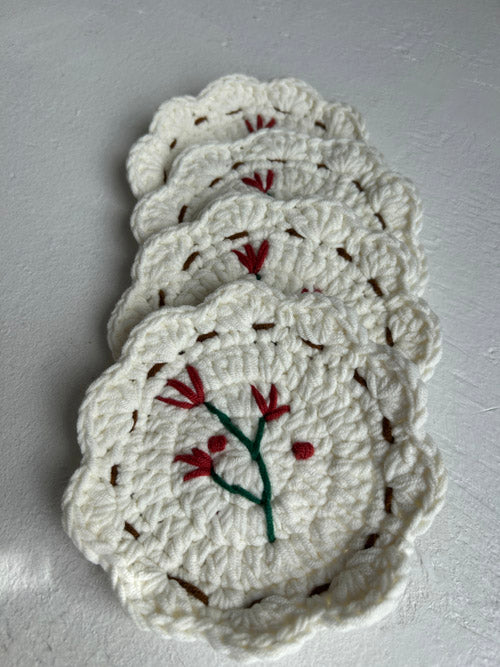 Set of white crocheted coasters with floral patterns on a gray surface