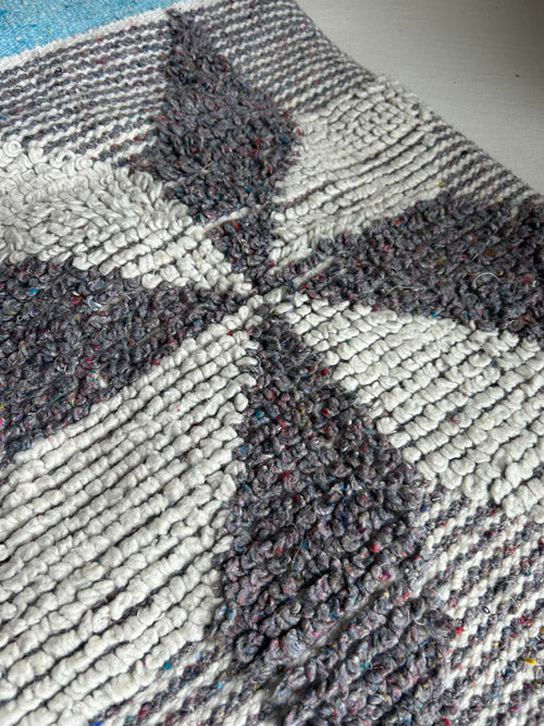 Close-up of a textured gray and white rug with geometric pattern