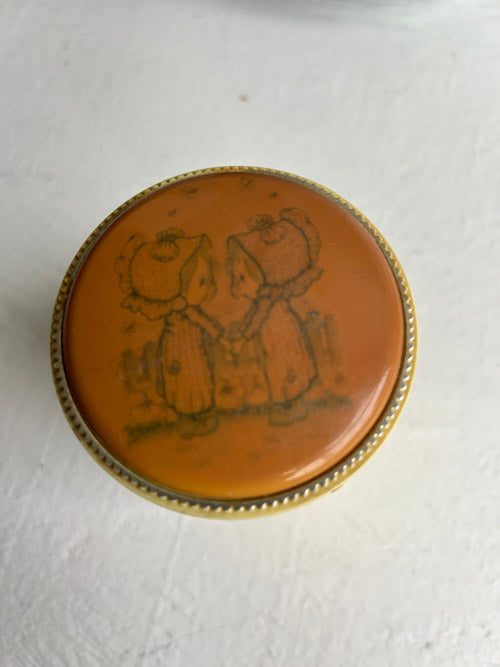 Round decorative lid with two girls illustration on a white background