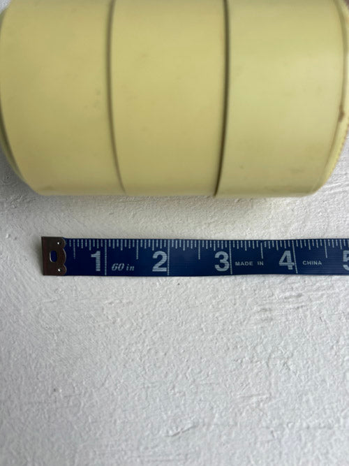 Roll of beige tape with a measuring tape below on a white background