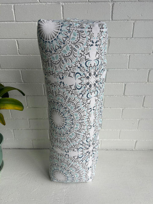 A long Yoga and Meditation Bolster with a floral pattern on a white surface and tiled wall background