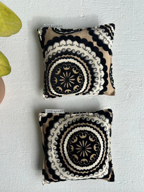 Two patterned knee pillows on a textured white surface